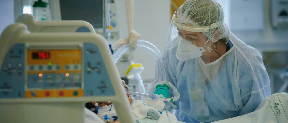 Ein medizinische Mitarbeiterin versorgt einen Intensivpatienten.