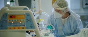 Ein medizinische Mitarbeiterin versorgt einen Intensivpatienten.