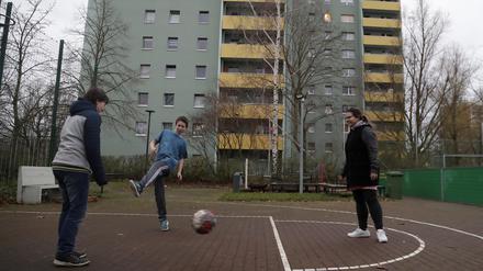 Kinder spielen vor der Arche Fussball. 