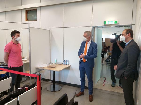 Drei Männer im Gespräch in einem Impfzentrum.