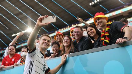 Joshua Kimmich macht ein Selfie mit Fans im Münchner Stadion, die keine Maske tragen.