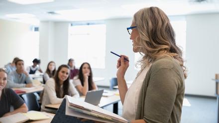 Eine junge Professorin unterrichtet Studierende in einem Seminarraum.