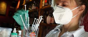 Eine medizinische Fachangestellte sortiert in der Revolte-Bar im Berliner Bezirk Friedrichshain Spritzen mit dem Impfstoff Johnson &amp; Johnson in einem Glas.