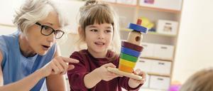 Eine Kitaerzieherin im Gespräch mit einem Mädchen im Vorschulalter.