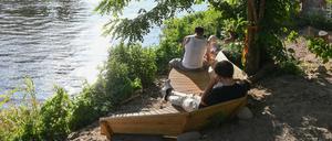 Im Licht der untergehenden Sonne sitzen Besucher im Open-Air-Bereich vom Veranstaltungsort Holzmarkt an der Spree.