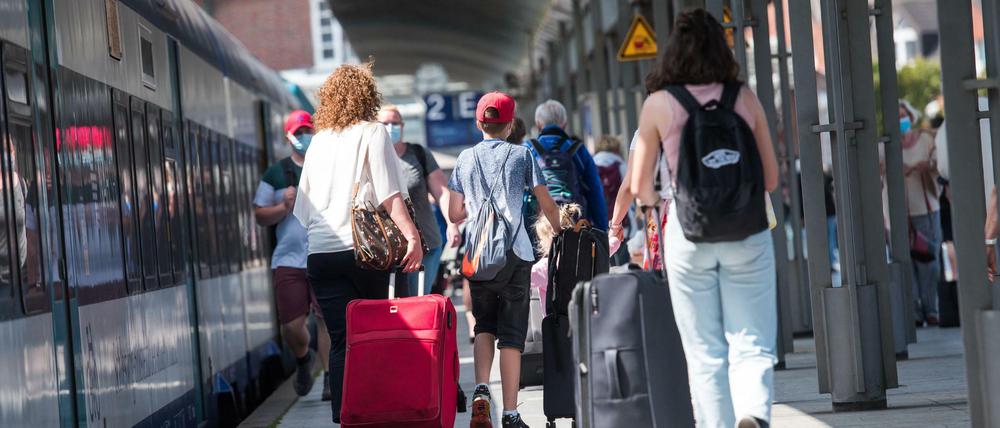 Reisende gehen am Bahnhof Westerland nach ihrer Ankunft mit dem Zug über den Bahnsteig.
