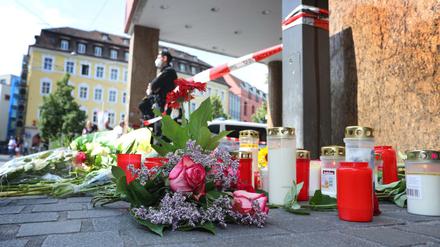 Ein Polizist steht in Würzburg neben Kerzen und Blumen.
