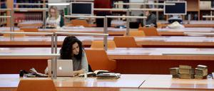 Eine junge Wissenschaftlerin sitzt in einem Lesesaal der Staatsbibliothek zu Berlin an ihrem Laptop.