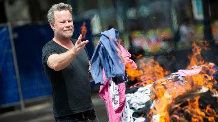 Fernsehjournalist Jenke von Wilmsdorff wirft für eine Recherche Altkleidung in ein Feuer auf dem Rudolfplatz.