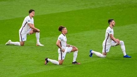 Englische Spieler knien vor dem Anpfiff auf dem Rasen.