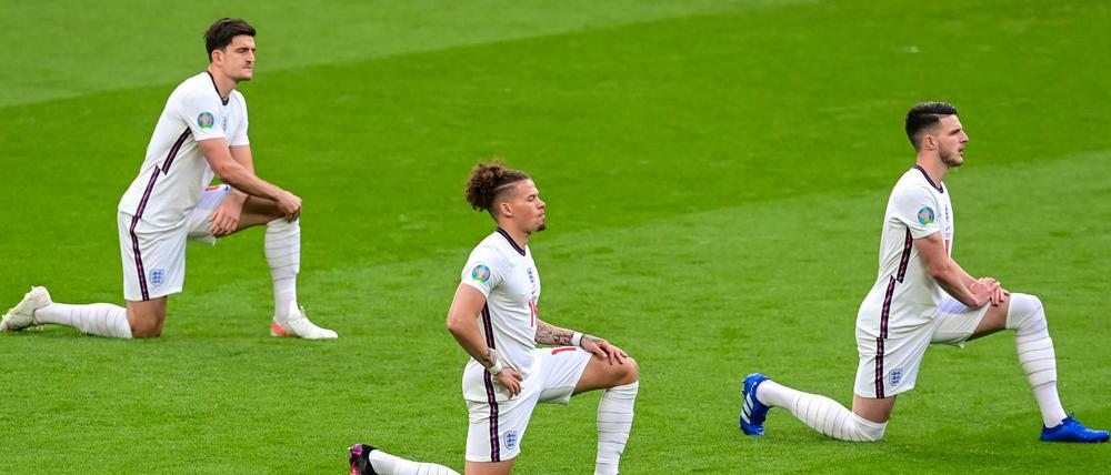 Englische Spieler knien vor dem Anpfiff auf dem Rasen.
