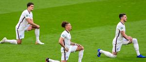 Englische Spieler knien vor dem Anpfiff auf dem Rasen.