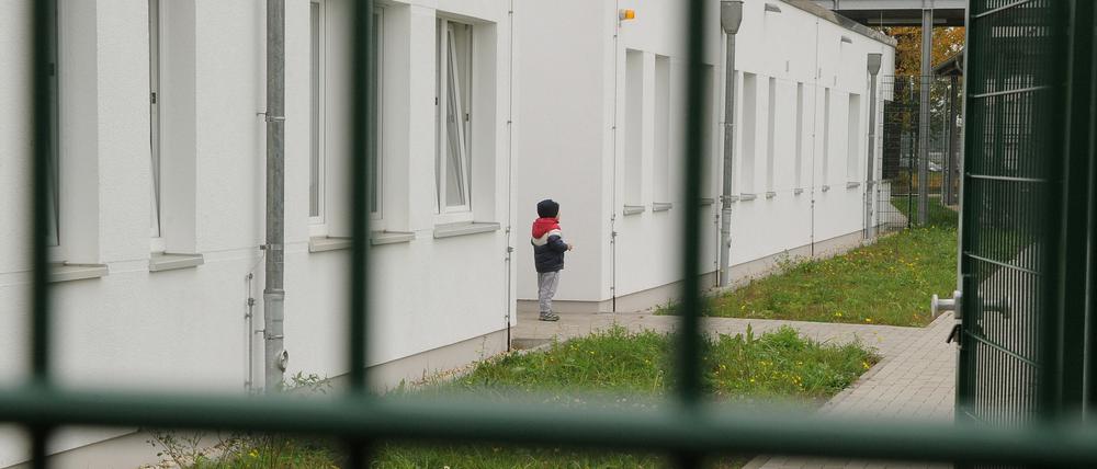 Ein kleiner Junge steht vor einer Flüchtlingsunterkunft.