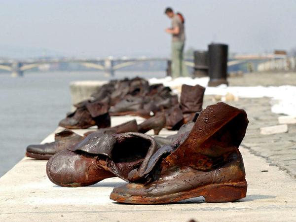 In Metall gegossene Stiefel stehen an einem Flussufer.