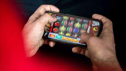 Auf einem Smartphone spielt ein Mann ein Online-Spiel.