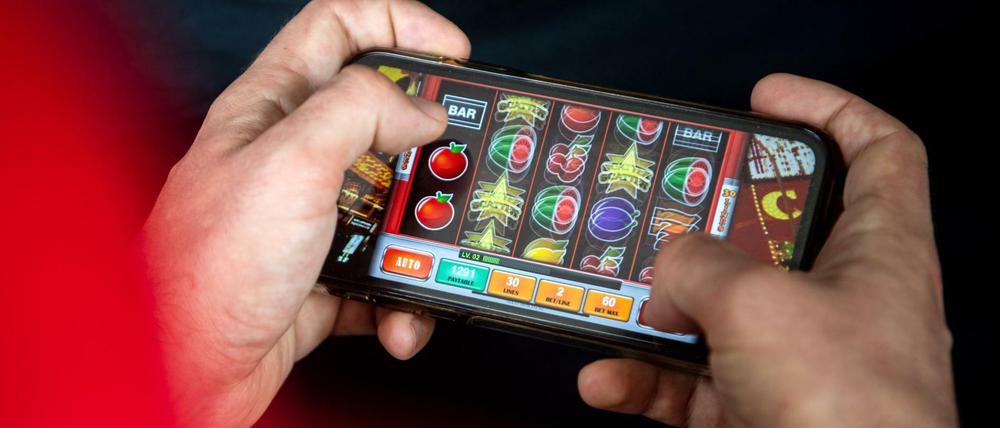 Auf einem Smartphone spielt ein Mann ein Online-Spiel.