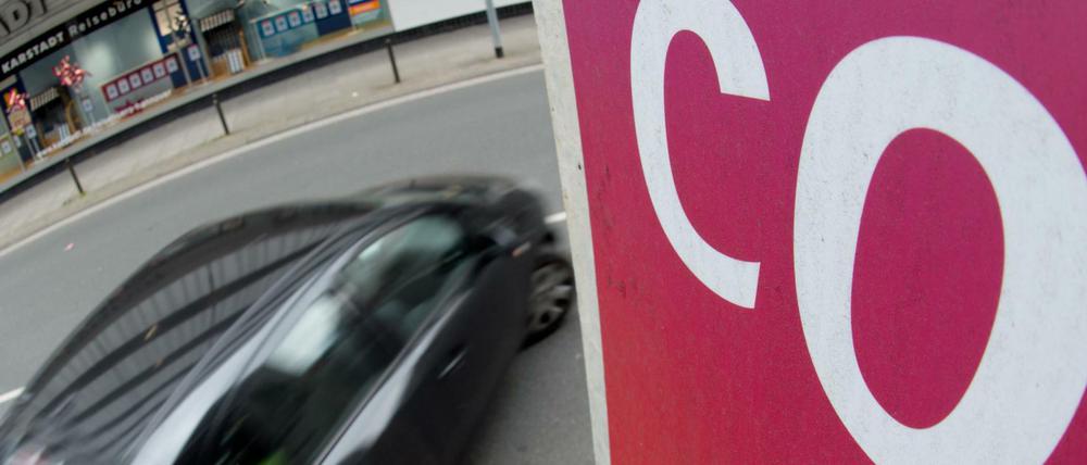 Ein Auto fährt an einem Schild mit Aufschrift "CO2" vorbei.