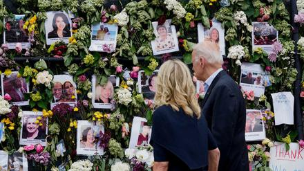 Joe und Jill Biden betrachten eine mit Blumen und Fotos der Vermissten bedeckte Gedenkwand.