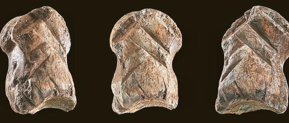 Ein etwa rechteckiges Knochenstück von drei verschiedenen Seiten, in dessen Oberfläche abgewinkelte Schnitzereien eingefügt wurden.