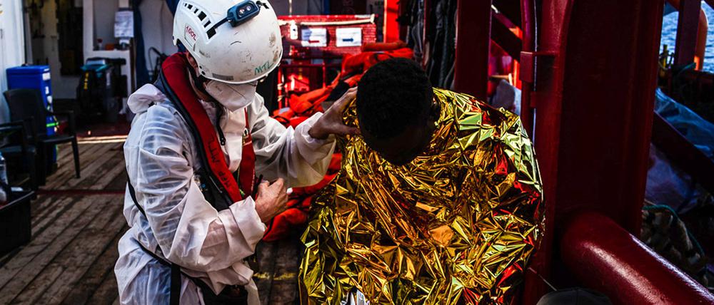 Ein Mitarbeiter des Seenotrettungsschiffs „Ocean Viking“ versorgt gerettete Migranten.