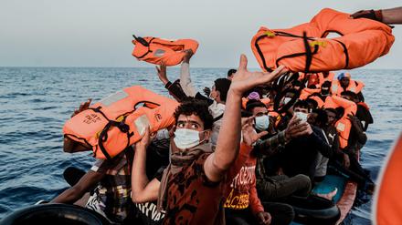 Ein Helfer versorgt Migranten mit Rettungswesten.