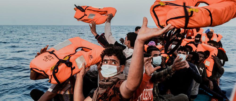 Ein Helfer versorgt Migranten mit Rettungswesten.