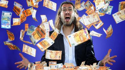 Junger Mann wirft Geldscheine in die Luft.