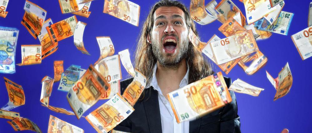 Junger Mann wirft Geldscheine in die Luft.
