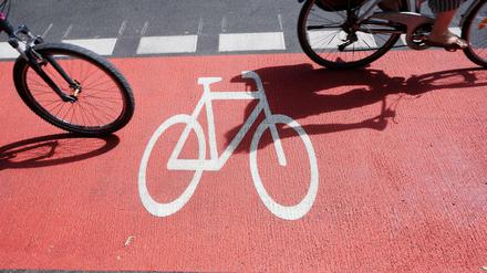 Zwei Personen nutzen mit ihren Drahteseln den rot gekennzeichneten neuen Fahrradstreifen am Kottbusser Damm. Wie kann der Ausbau der gesicherten Wege schneller gehen?