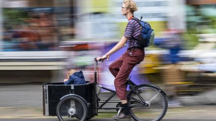 In einer Sänfte durch Neukölln wie früher die Könige: Immer mehr Eltern setzen sich für ihr Kind aufs Lastenrad.