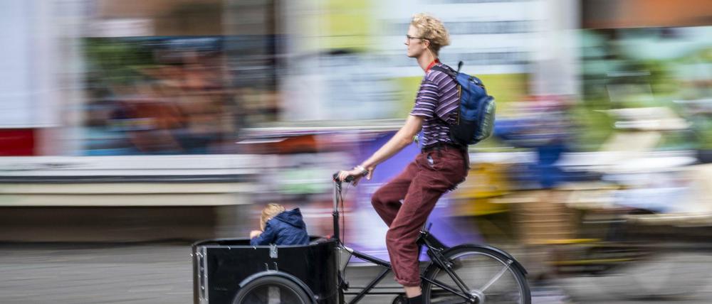 In einer Sänfte durch Neukölln wie früher die Könige: Immer mehr Eltern setzen sich für ihr Kind aufs Lastenrad.