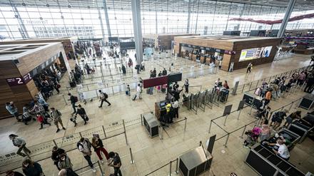 Reisende stehen am Flughafen BER im Terminal. 