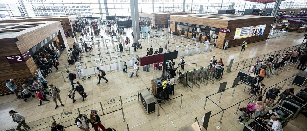 Reisende stehen am Flughafen BER im Terminal.