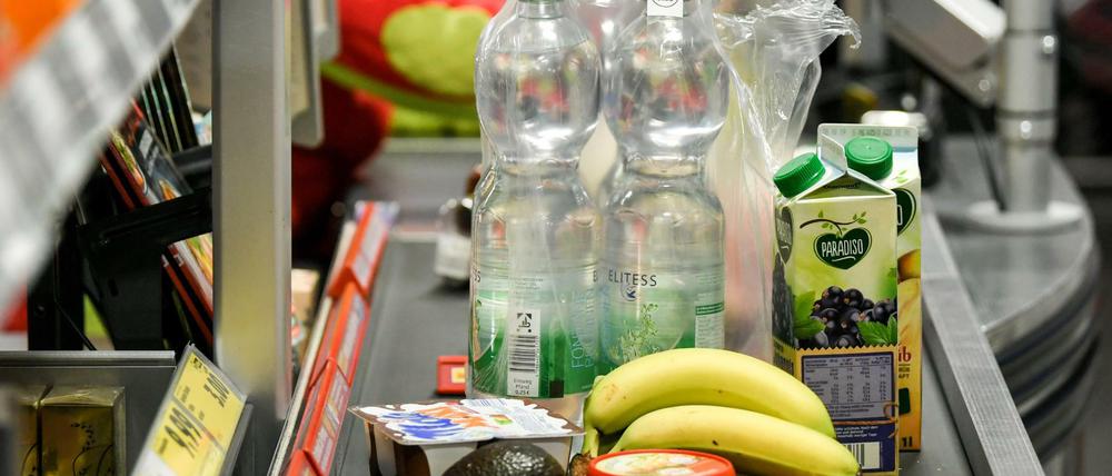 Lebensmittel liegen auf dem Band an einer Kasse in einem Supermarkt.