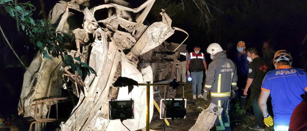 Rettungskräfte stehen neben dem ausgebrannten Kleinbus.