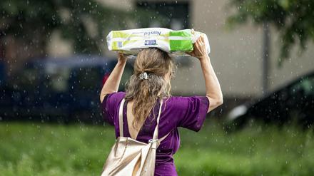 Eine Frau schützt sich am 15. Juli vor dem starken Regenfall mit einer Packung Klopapier.
