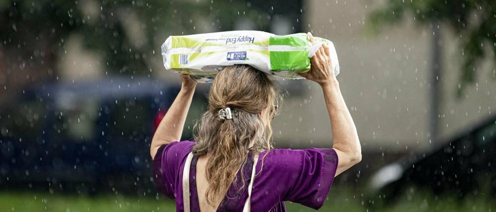 Eine Frau schützt sich am 15. Juli vor dem starken Regenfall mit einer Packung Klopapier.