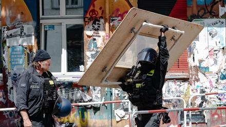 Ein Polizeibeamter trägt ein übergroßes Schutzschild aus dem Haus Rigaer Straße 94.