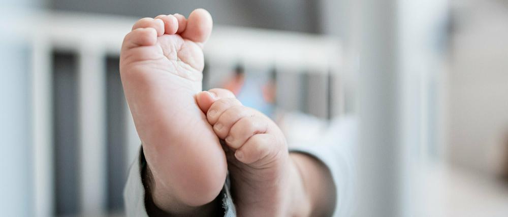 Die Füße eines Babys sind in einem Kinderbett zu sehen. Im vergangenen Jahr wurden in Deutschland weniger Kinder geboren als im Jahr davor.
