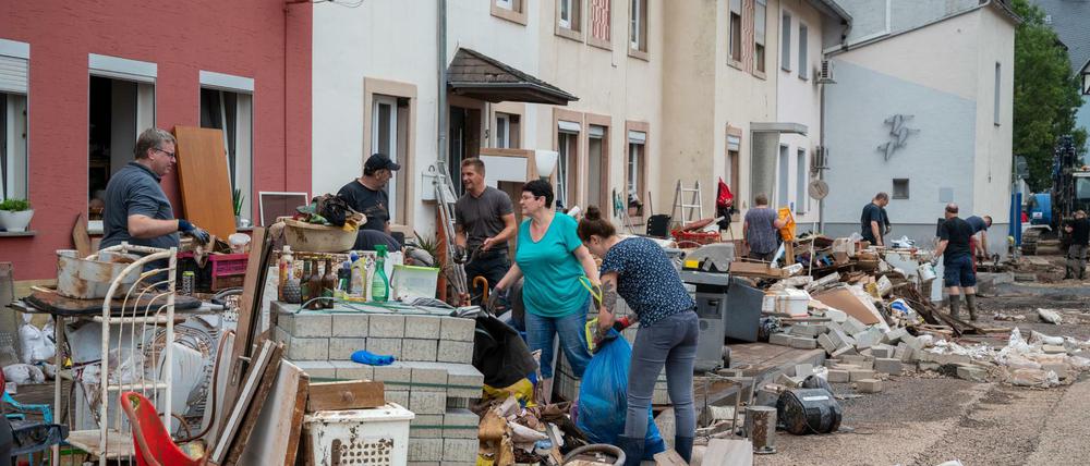 Menschen räumen im Stadtteil Ehrang die Schäden nach dem Hochwasser der Kyll auf.