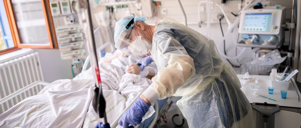 Ein Intensivpfleger versorgt auf der Intensivstation eines Krankenhauses eine an Covid-19 erkrankte Patientin.
