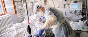 Ein Intensivpfleger versorgt auf der Intensivstation eines Krankenhauses eine an Covid-19 erkrankte Patientin.