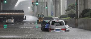 Menschen schieben nach starken Regenfällen in Zhengzhou in der zentralen chinesischen Provinz Henan einen Lieferwagen durch Hochwasser. 