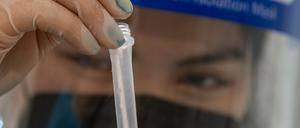 Die Mitarbeiterin eines Testzentrums bearbeitet einen Abstrich.