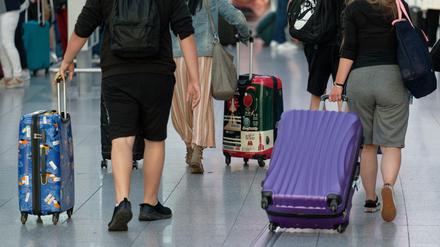 Reisende gehen ein einem Flughafen mit Koffern durch die Abflughalle.