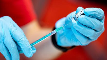 Ein Notfallsanitäter der DLRG zieht an der Universität Potsdam den Corona-Impfstoff von Biontech in eine Spritze.