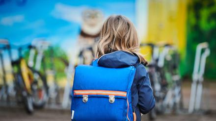 Ein Schüler steht mit Schulranzen über den Schulhof einer Grundschule in Prenzlauer Berg. (Symbolbild)