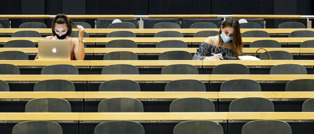 Studentinnen mit Mund-Nasen-Schutz sitzen in einem Hörsaal.
