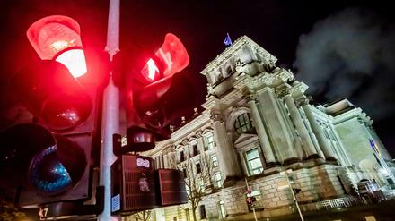 Eine rote Ampel leuchtet vor dem Reichstagsgebäude bei Nacht.