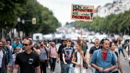 Demonstranten gegen die Corona-Maßnahmen laufen die Bismarckstraße mit einem Schild mit der Aufschrift "Nein zur Impfapartheid nie wieder Faschismus" entlang.